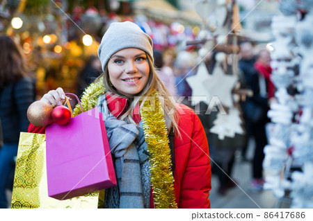Young female near counter with xmas gifts on street market Young female near counter with xmas gifts on street market 86417686