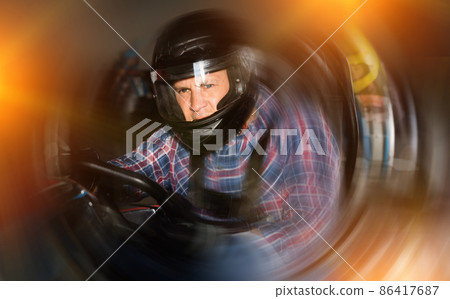 Portrait of male racer in helmet driving kart on track Portrait of male racer in helmet driving kart on track 86417687