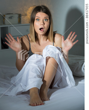 Worried young woman is oversleep, sitting on bed in bedroom 86417935