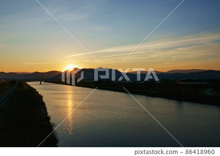 一個冬天的早晨，冉冉升起的太陽和反射晨光的河面 86418960