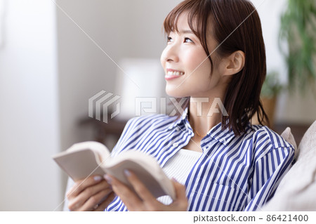 一個女人坐在沙發上和閱讀 一個女人坐在沙發上和閱讀 86421400