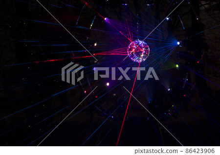 Mirrored Disco Ball and bright beams at the night party. Party attribute reflects Lazer lights. Abstract background with defocused rays. Night club atmosphere. Installation at Vilnius light festival 86423906