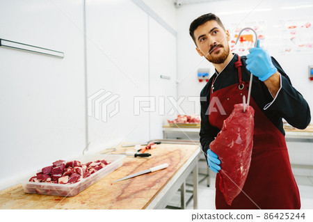 Butcher man holding meat on hook to cut and sell it Butcher man holding meat on hook to cut and sell it 86425244