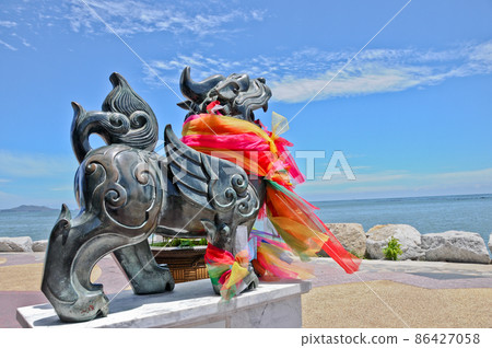 Dark metallic bronze brass black metal Asian lion statue with vast blue ocean in sunny day Dark metallic bronze brass black metal Asian lion statue with vast blue ocean in sunny day 86427058