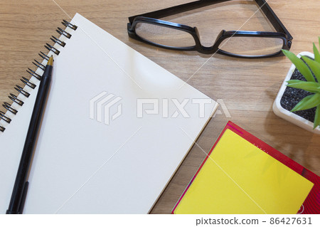Notepad with yellow note, potted plant and study glasses. Flat lay Notepad with yellow note, potted plant and study glasses. Flat lay 86427631