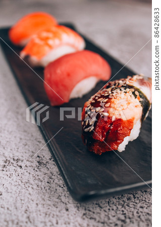 Set of traditional japanese nigiri sushi on white marble table background - with raw tuna, salmon fish, shrimp and eel. Asian food online delivery and sushi bar lunch menu concept. Vertical image 86428633