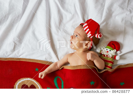 Little newborn baby, wearing Santa hat under blanket Little newborn baby, wearing Santa hat under blanket 86428877