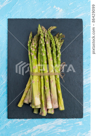 Green organic raw asparagus on dark background with copy space. Healthy raw vegan food Green organic raw asparagus on dark background with copy space. Healthy raw vegan food 86429099