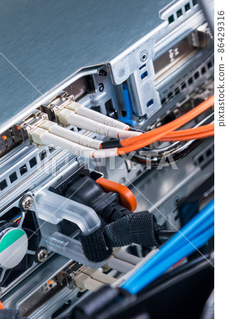 detail of server rack with fiber optic cables attached to front panel switch ports 86429316