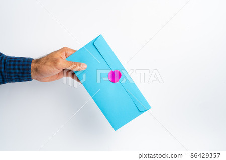 Male hand holding closed envelope above the white surface Male hand holding closed envelope above the white surface 86429357