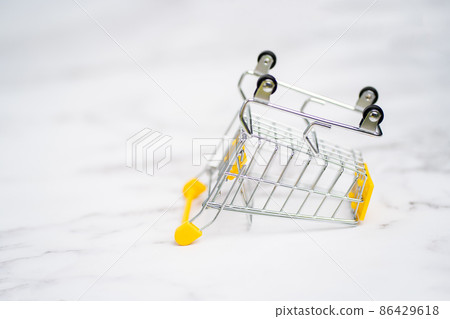 Empty inverted shopping cart on white marble background. Stainless steel shopping trolley upside down. Business, mall, market, shopping concept. Empty inverted shopping cart on white marble background. Stainless steel shopping trolley upside down. Business, mall, market, shopping concept. 86429618
