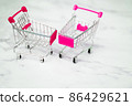 Shopping, purchases, supermarket, sale, mall concept. Two empty metal small miniature toy shopping trolley on light background. Selective focus. 86429621