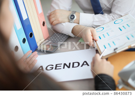 Man and woman sitting at table with documents with agenda closeup Man and woman sitting at table with documents with agenda closeup 86430873