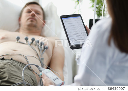 Doctor taking cardiogram to patient on couch in clinic closeup 86430907