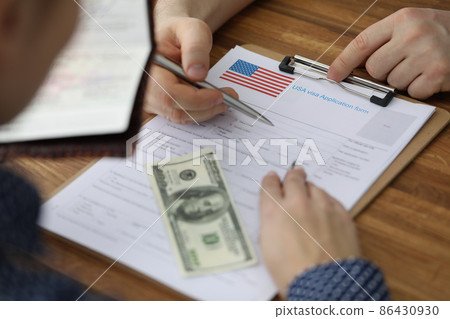 Man filling out paperwork for american visa with help of consultant closeup 86430930
