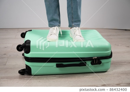 Woman standing with her feet on a suitcase. Woman standing with her feet on a suitcase. 86432400