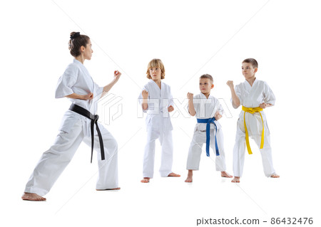 Group of kids, boys, taekwondo athletes wearing doboks training with master isolated on white background. Concept of sport, martial arts 86432476