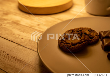 Chocolate chip cookies on a plate and chocolates, cups, table lamps 86432661