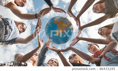 Earth conservation concept. 11 girls surround the rotating earth globe with their palms. 86433285