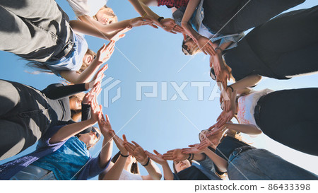 A group of girls makes a circle from their palms. 86433398