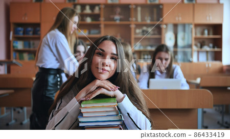 A student poses with textbooks at her desk in her class. A student poses with textbooks at her desk in her class. 86433419
