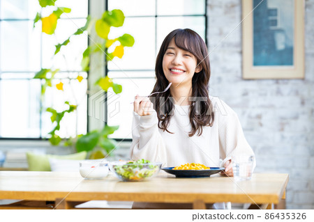 Young woman eating pasta at home 86435326