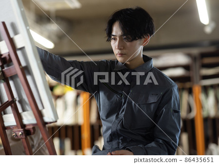 A young student wearing a coverall and drawing an oil painting 86435651