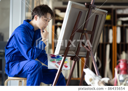 A young student wearing a coverall and drawing an oil painting A young student wearing a coverall and drawing an oil painting 86435654