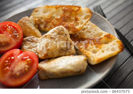 toasted pieces of chicken breast, toast and tomatoes on plate 86437075