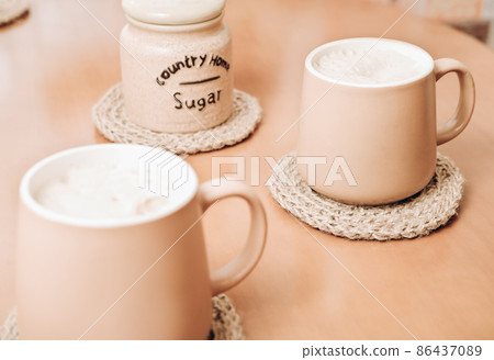 coffee mugs on a jute coasters on a table. hand made knitted kitchen accessories. natural home decor. 86437089