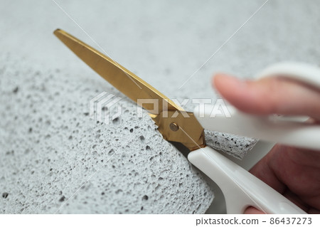 Female hand cutting the old shii mat with scissors 86437273