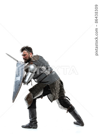 Portrait of brave medieval warrior, knight in special armor protecting himself with shield and sword isolated over white studio backgrond 86438309