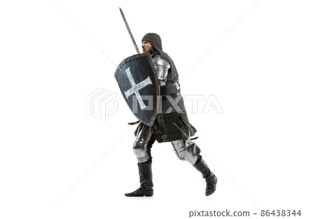 Portrait of concentrated man, medieval warrior in chain armor with sword and shield attacking enemy isolated over white studio background Portrait of concentrated man, medieval warrior in chain armor with sword and shield attacking enemy isolated over white studio background 86438344