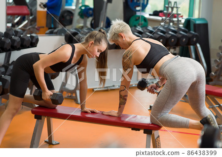 A young woman is doing fitness with a trainer at the GYM A young woman is doing fitness with a trainer at the GYM 86438399