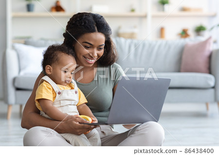 Modern Technologies. Young Black Woman With Infant Baby Using Laptop At Home Modern Technologies. Young Black Woman With Infant Baby Using Laptop At Home 86438400