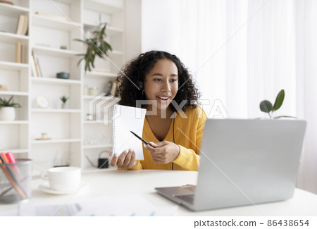 Remote lesson. Happy young black female student showing notebook into laptop webcam during college class at home 86438654