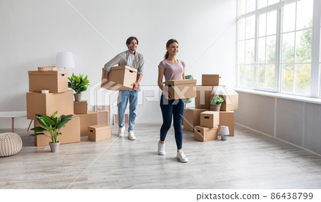 Satisfied happy millennial caucasian male and female carry cardboard boxes, enjoy moving in empty apartment Satisfied happy millennial caucasian male and female carry cardboard boxes, enjoy moving in empty apartment 86438799