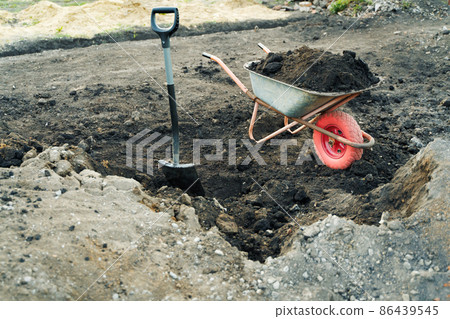 Working with garden tools, shovel and wheelbarrow on the site of a country house. Preparation for construction work. 86439545