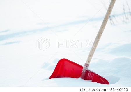 Close up of big red plastic showel in the process of removing snow in winter Close up of big red plastic showel in the process of removing snow in winter 86440400