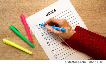Woman writing down her goals list by colored markers 86441188