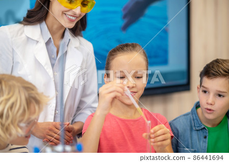 Girl adding liquid from pipette to test tube 86441694