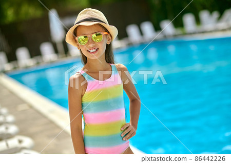Girl in sunglasses smiling at camera near pool 86442226
