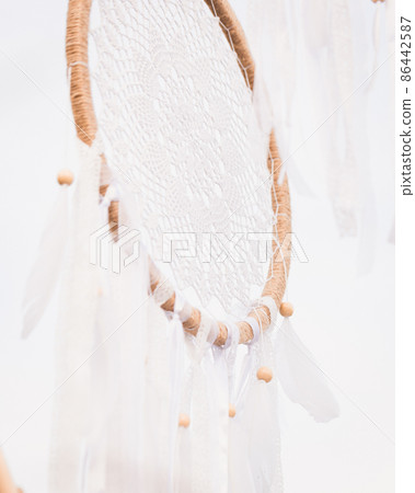 White cotton dreamcatcher at natural background, soft selective focus, toned White cotton dreamcatcher at natural background, soft selective focus, toned 86442587