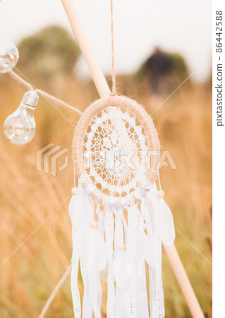 White cotton dreamcatcher at natural background, soft selective focus, toned White cotton dreamcatcher at natural background, soft selective focus, toned 86442588