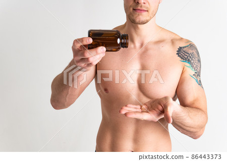 Fish oil is eaten by a man in the hands of vials and a glass bottle capsule vitamin, medicine tablet liver 3, gel cod. white fat, care female giving dieting 86443373