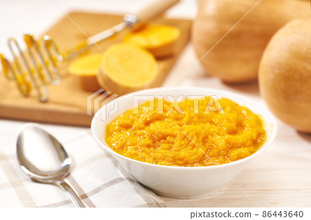 Pumpkin puree in a ceramic bowl, fresh pumpkin, squash, butternut close up on white kitchen table. Pumpkin puree in a ceramic bowl, fresh pumpkin, squash, butternut close up on white kitchen table. 86443640