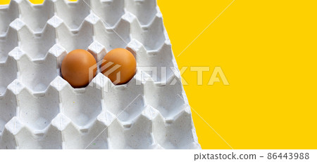 Chicken eggs in paper egg crate on yellow background. 86443988