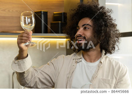 Arabian man checks stains on wineglasses after dishwasher 86445666