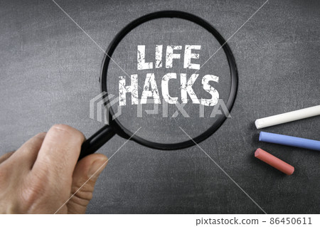 Life Hacks concept. Colored pieces of chalk and a magnifying glass on a chalkboard background Life Hacks concept. Colored pieces of chalk and a magnifying glass on a chalkboard background 86450611