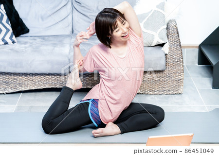 Young woman doing online yoga in the living room 86451049